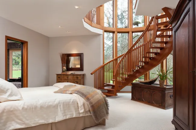 Деревянные лестницы в сочетании с панорамным остеклением оптически расширяют границы этой спальни, превращая ее в максимально светлое и воздушное пространство. 